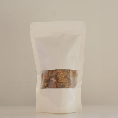 Bolsa de papel blanca con nueces peladas ecológicas en su interior