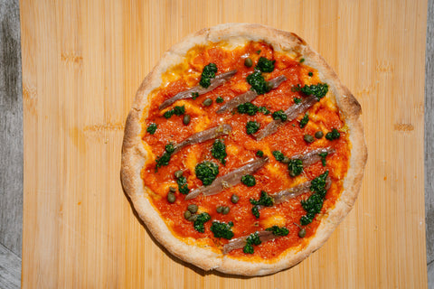 Pizza con salsa tomate, pesto de perejil, ajo, limón y anchoas