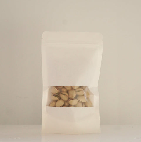 Bolsa blanca de papel con pistachos con cáscara ecológicos