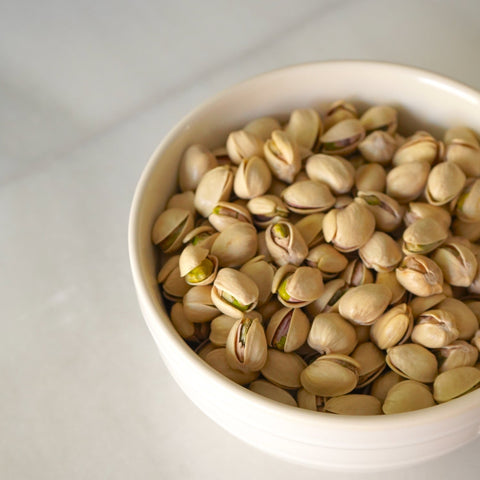 Cuenco blanco con pistachos con cáscara ecológicos